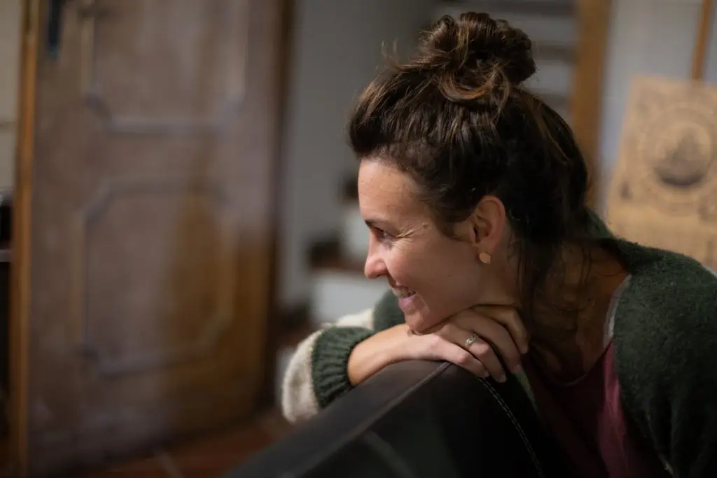 Femme souriante en communication animale avec un animal.